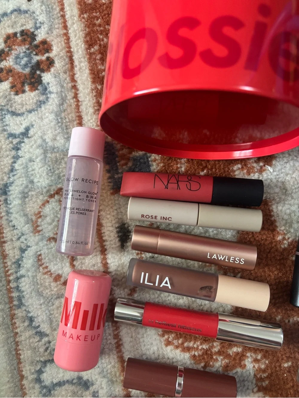 Glossier red mini bucket with mixed pink and mauve lip products